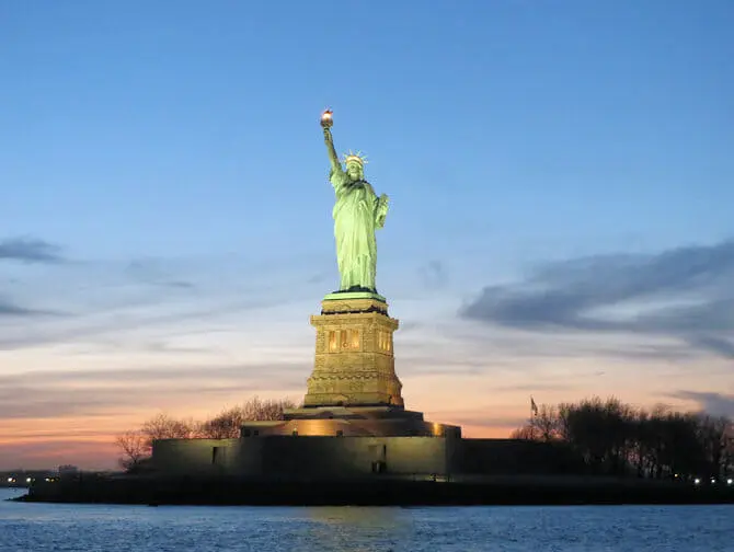 Estátua da Liberdade vista de um barco ao pôr-do-sol em Nova York